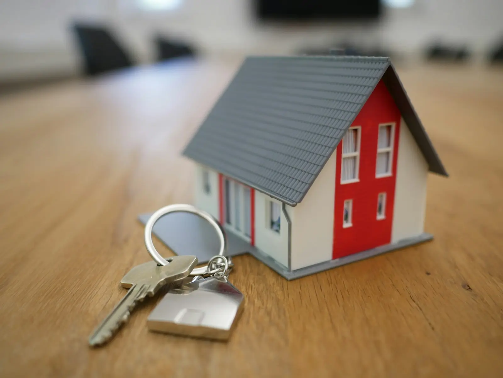 Miniature house model with house keys, representing home construction budgeting